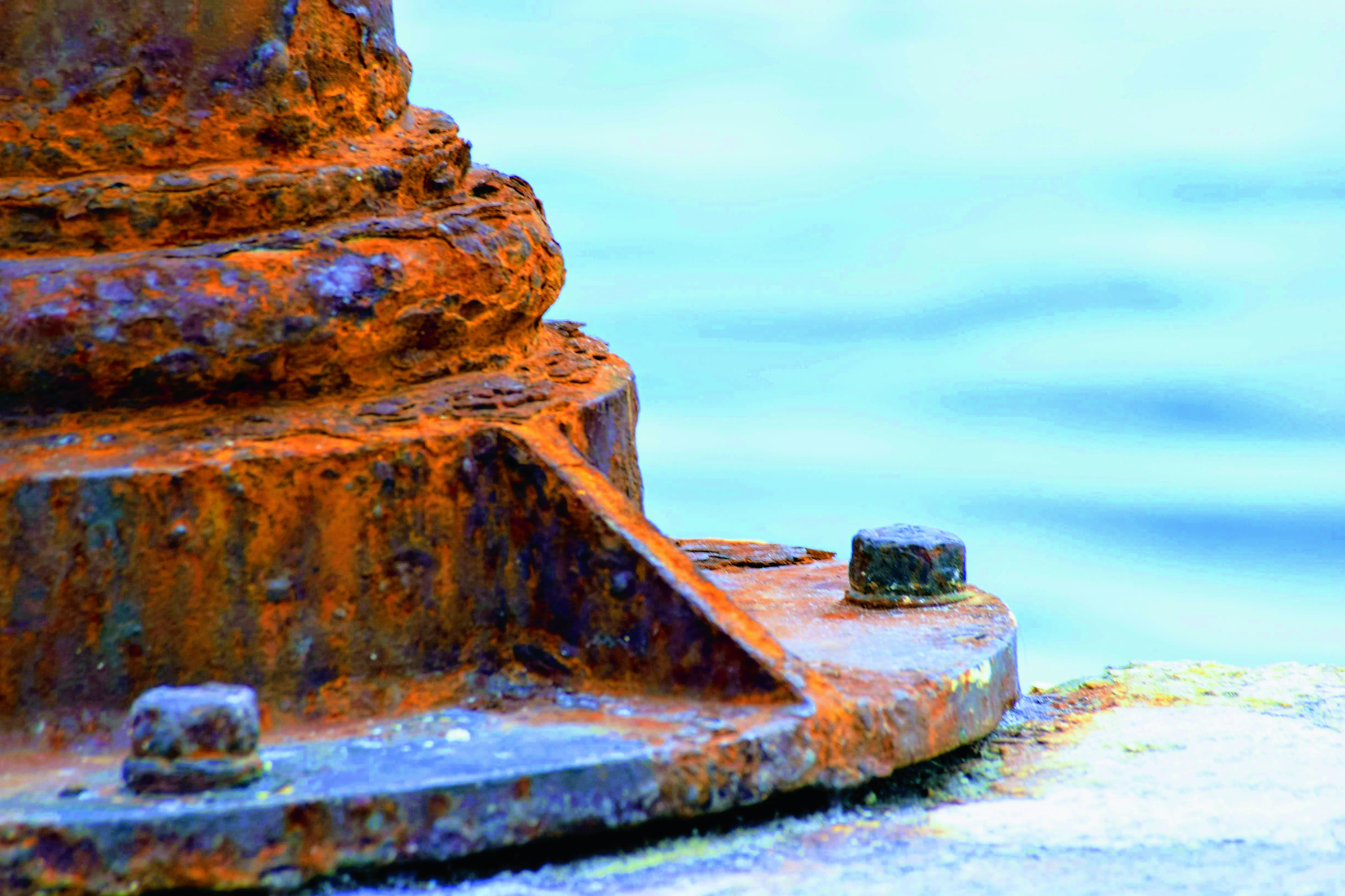 Ржавая металлическая опора у воды — пример коррозии от воздействия влаги